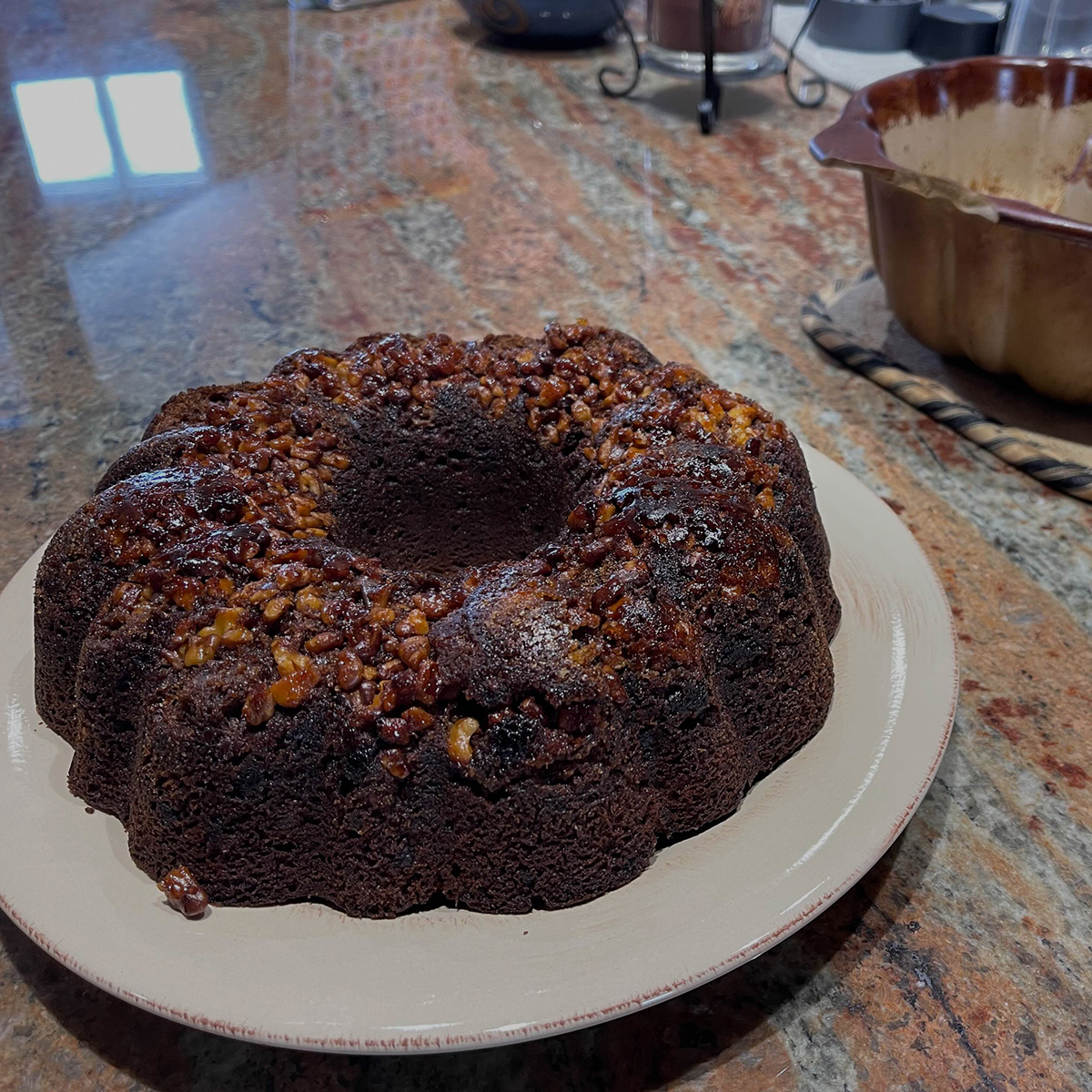 A loaf of banana bread topped with caramalized walnuts on a plate.