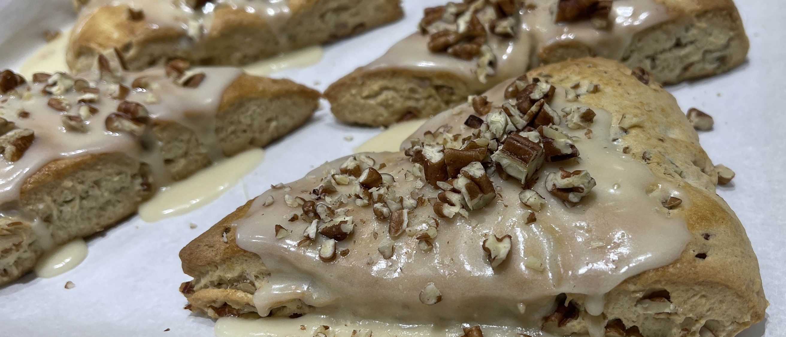 Close up on a maple pecan scone on a baking sheet with parchment.